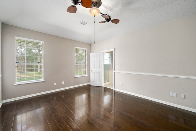 empty room with visible vents, a textured ceiling, baseboards, and wood finished floors