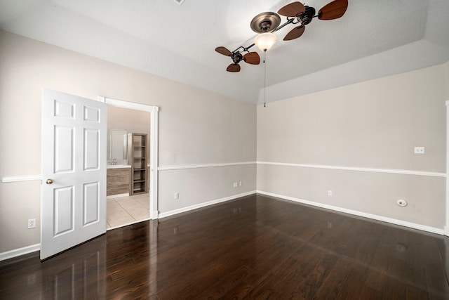 empty room with ceiling fan, wood finished floors, lofted ceiling, and baseboards