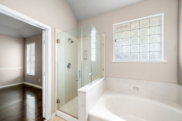 full bath featuring a stall shower, baseboards, lofted ceiling, wood finished floors, and a bath