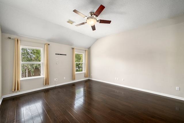 empty room featuring dark wood-style floors, lofted ceiling, visible vents, and plenty of natural light