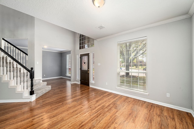 foyer entrance with crown molding, stairs, baseboards, and wood finished floors