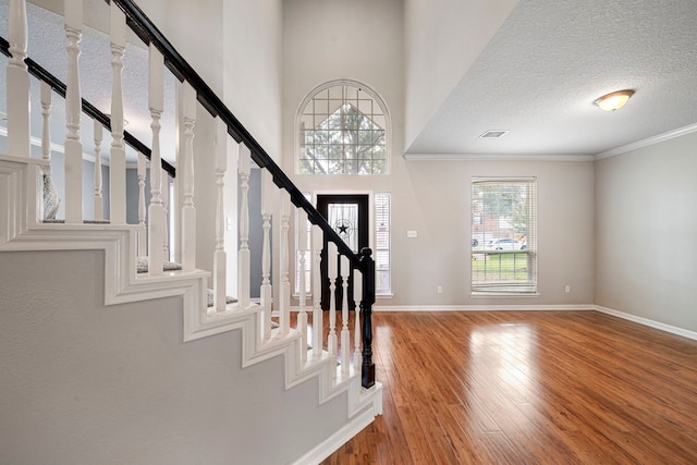 foyer entrance with stairs, a textured ceiling, baseboards, and wood finished floors