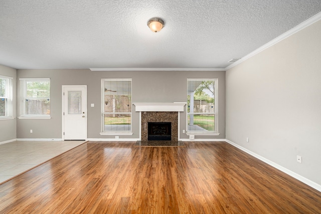 unfurnished living room featuring plenty of natural light, a textured ceiling, a premium fireplace, and wood finished floors