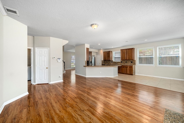 unfurnished living room with light wood-style floors, baseboards, and visible vents