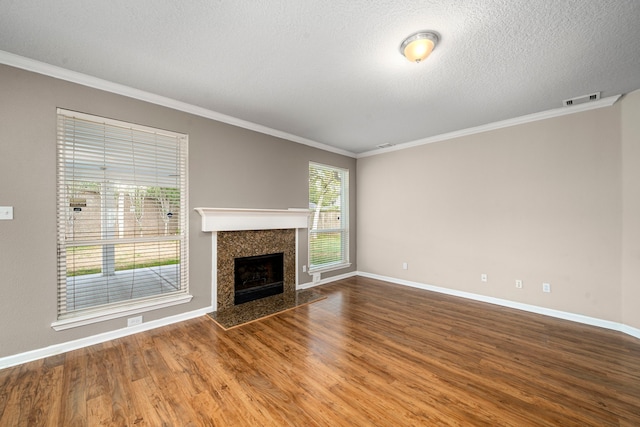 unfurnished living room featuring a textured ceiling, a fireplace, wood finished floors, visible vents, and ornamental molding