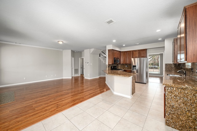 kitchen featuring stainless steel appliances, tasteful backsplash, visible vents, light tile patterned flooring, and a sink