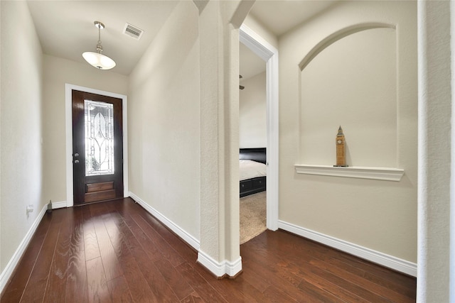 foyer with dark wood-style floors, arched walkways, visible vents, and baseboards