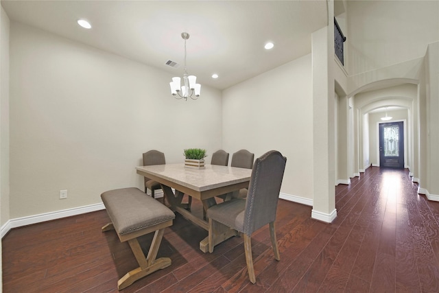 dining room with arched walkways, dark wood-style flooring, baseboards, and an inviting chandelier