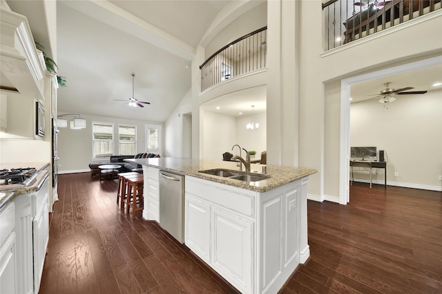 kitchen with baseboards, dishwasher, dark wood-style floors, light stone countertops, and a sink