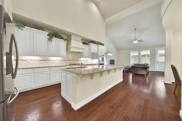 kitchen with a sink, custom range hood, appliances with stainless steel finishes, and dark wood-style flooring