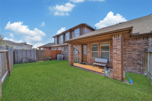 back of property featuring brick siding, a shingled roof, a lawn, cooling unit, and a fenced backyard