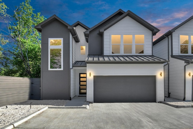 view of front of home featuring a garage, a standing seam roof, fence, and metal roof