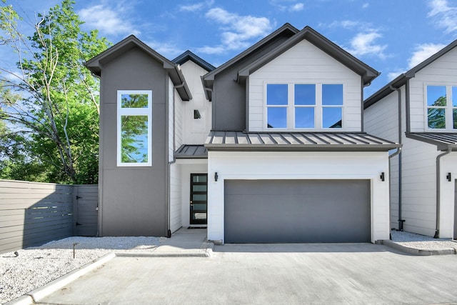 view of front of home featuring concrete driveway, a standing seam roof, metal roof, fence, and a garage