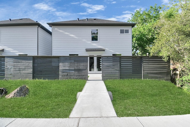 view of front of home with french doors, fence, and a front lawn