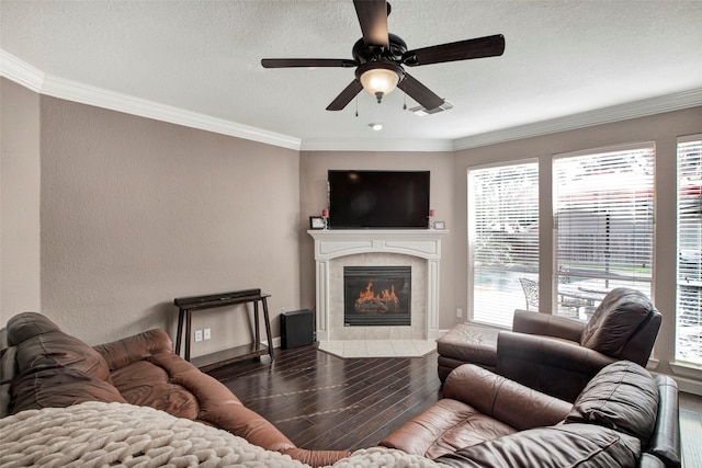 living room featuring ceiling fan, a tile fireplace, crown molding, and wood finished floors