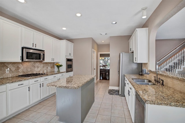 kitchen featuring white cabinets, a kitchen island, stainless steel appliances, and a sink