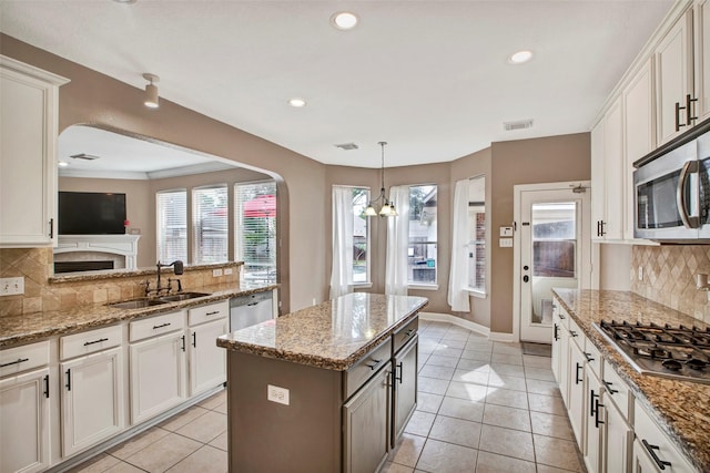 kitchen with light tile patterned floors, a kitchen island, appliances with stainless steel finishes, and a sink