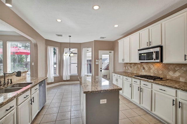 kitchen featuring light tile patterned flooring, appliances with stainless steel finishes, a sink, and a center island