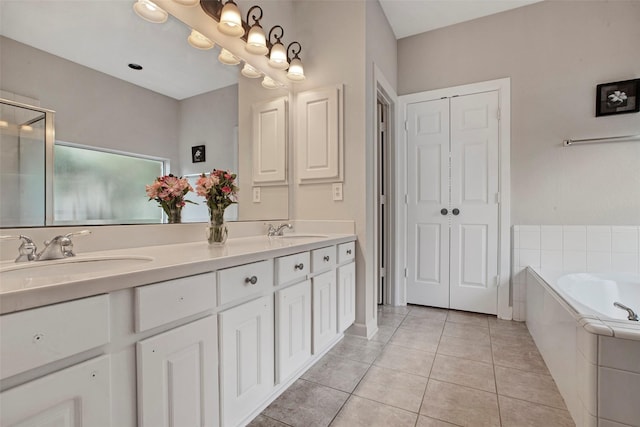 full bath featuring tile patterned flooring, double vanity, a sink, and a bath