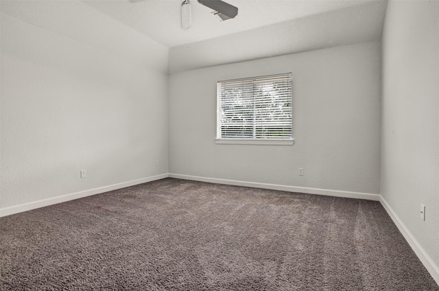 spare room with carpet, baseboards, vaulted ceiling, and a ceiling fan