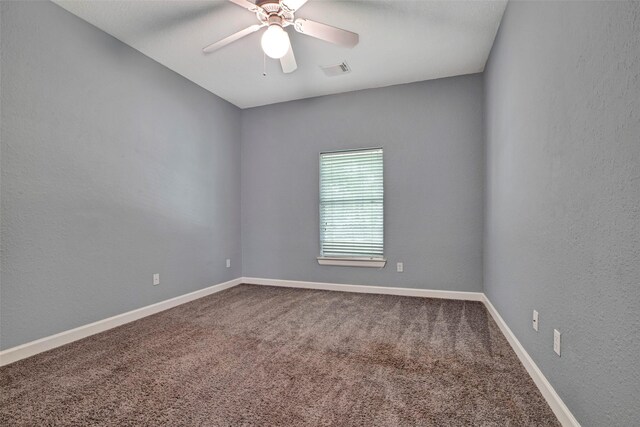 carpeted spare room with baseboards, visible vents, a ceiling fan, and a textured wall