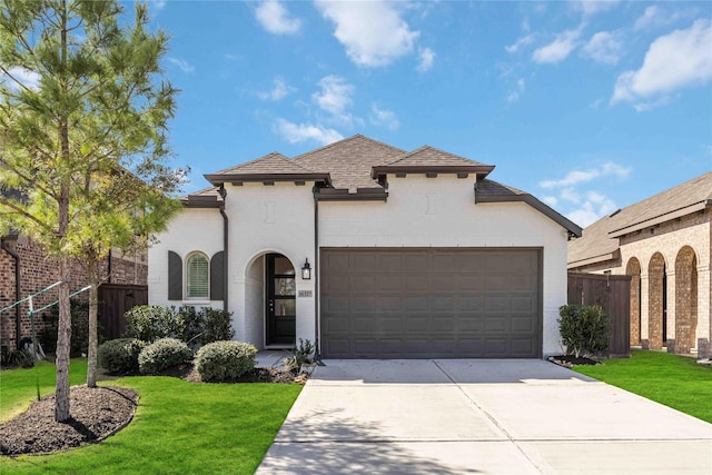 view of front of property featuring concrete driveway, an attached garage, fence, and a front yard