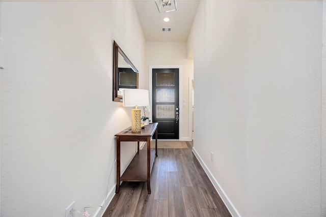 doorway with baseboards, visible vents, and dark wood finished floors