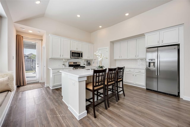 kitchen featuring a breakfast bar area, wood finished floors, stainless steel appliances, light countertops, and a sink