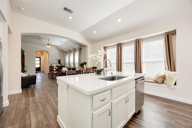 kitchen featuring arched walkways, lofted ceiling, a sink, visible vents, and dishwasher