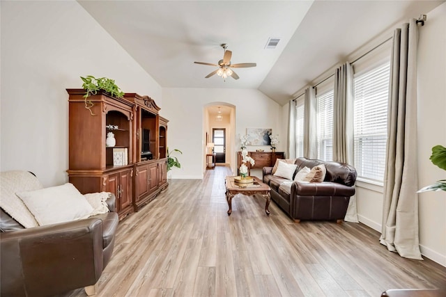 sitting room featuring arched walkways, vaulted ceiling, visible vents, and light wood-style floors