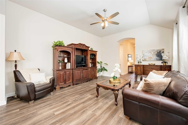 living room featuring arched walkways, light wood-style floors, vaulted ceiling, ceiling fan, and baseboards