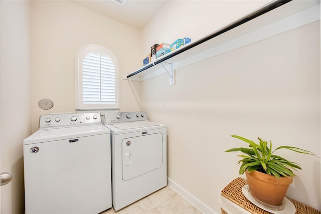 laundry room with laundry area, light tile patterned flooring, baseboards, and washing machine and clothes dryer