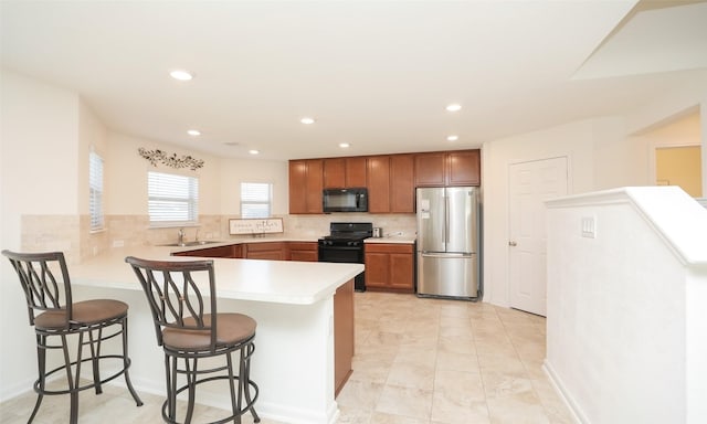 kitchen featuring black appliances, backsplash, a peninsula, and light countertops