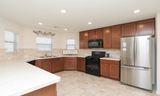 kitchen featuring black appliances, tasteful backsplash, a sink, and light countertops