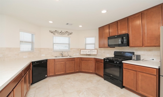 kitchen with black appliances, visible vents, brown cabinetry, and a sink