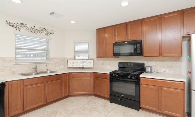 kitchen featuring tasteful backsplash, visible vents, light countertops, black appliances, and a sink