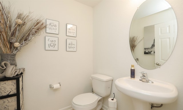 half bath featuring a sink, toilet, and baseboards