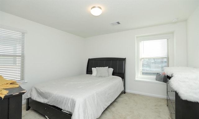 bedroom with baseboards, visible vents, and light colored carpet