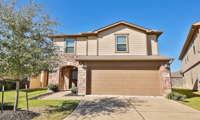 traditional-style house with an attached garage, driveway, brick siding, and a front yard