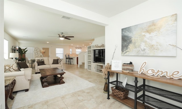 living area featuring visible vents, ceiling fan, and stairway