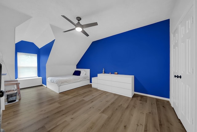 unfurnished bedroom featuring a closet, baseboards, vaulted ceiling, and wood finished floors