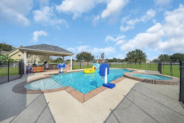 view of pool featuring an outdoor kitchen, fence, a pool with connected hot tub, a gazebo, and a patio area