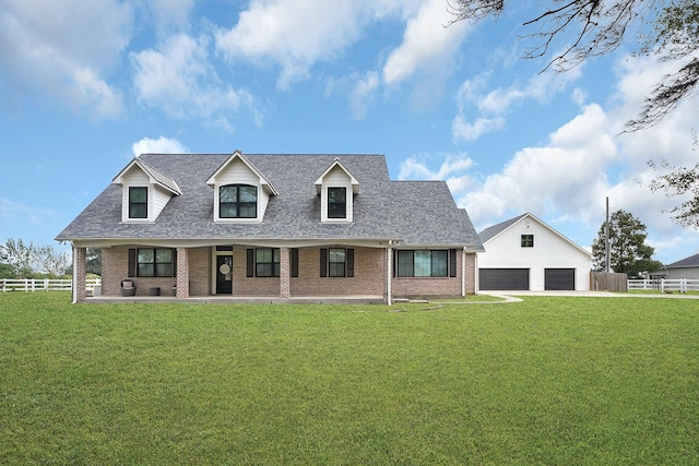 cape cod house with brick siding, a detached garage, fence, and a front yard