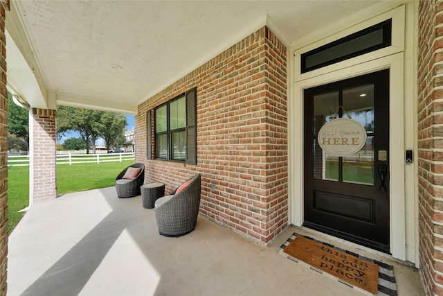 view of exterior entry featuring covered porch and brick siding