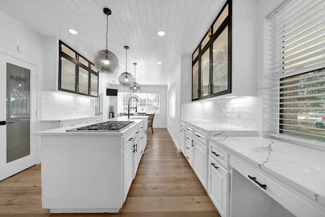 kitchen with white cabinets, a kitchen island with sink, and light wood-style flooring