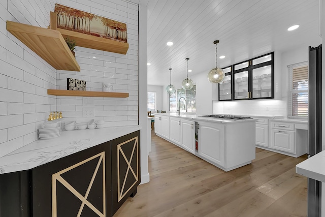 kitchen with white cabinets, decorative backsplash, open shelves, and a sink