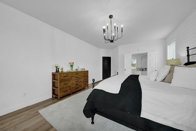 bedroom with a chandelier, wood finished floors, and baseboards