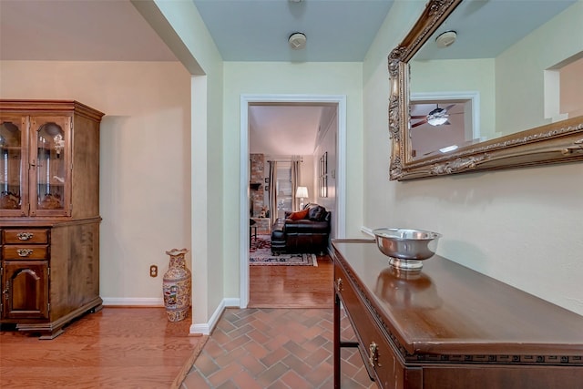 corridor featuring brick floor and baseboards