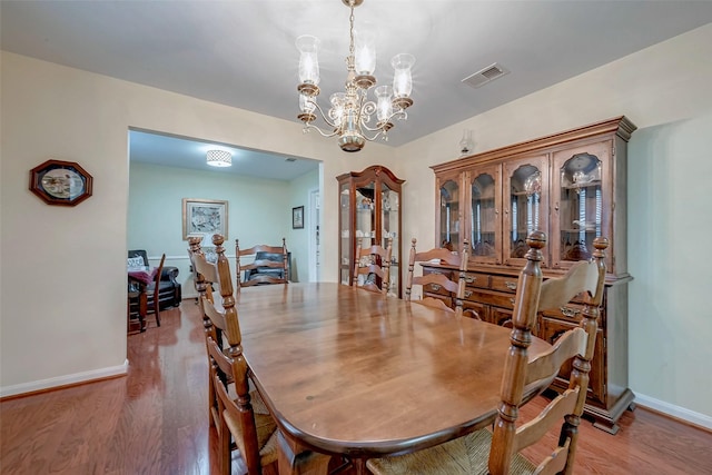 dining area with a chandelier, wood finished floors, and baseboards