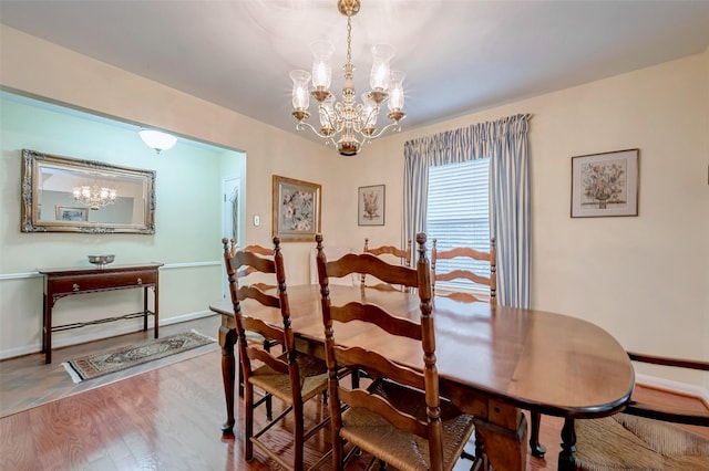 dining space with wood finished floors, baseboards, and an inviting chandelier